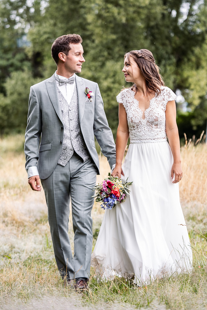 Foto von Lisa Werner Fotografie, Hochzeit, Brautpaarshooting, Brautpaar läuft über eine Wiese